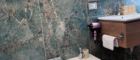 Un baño con bidé, inodoro, lavabo con espejo y un perchero para toallas.