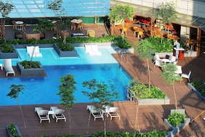 A rooftop pool area with lounge chairs, a small pool, and surrounding greenery.