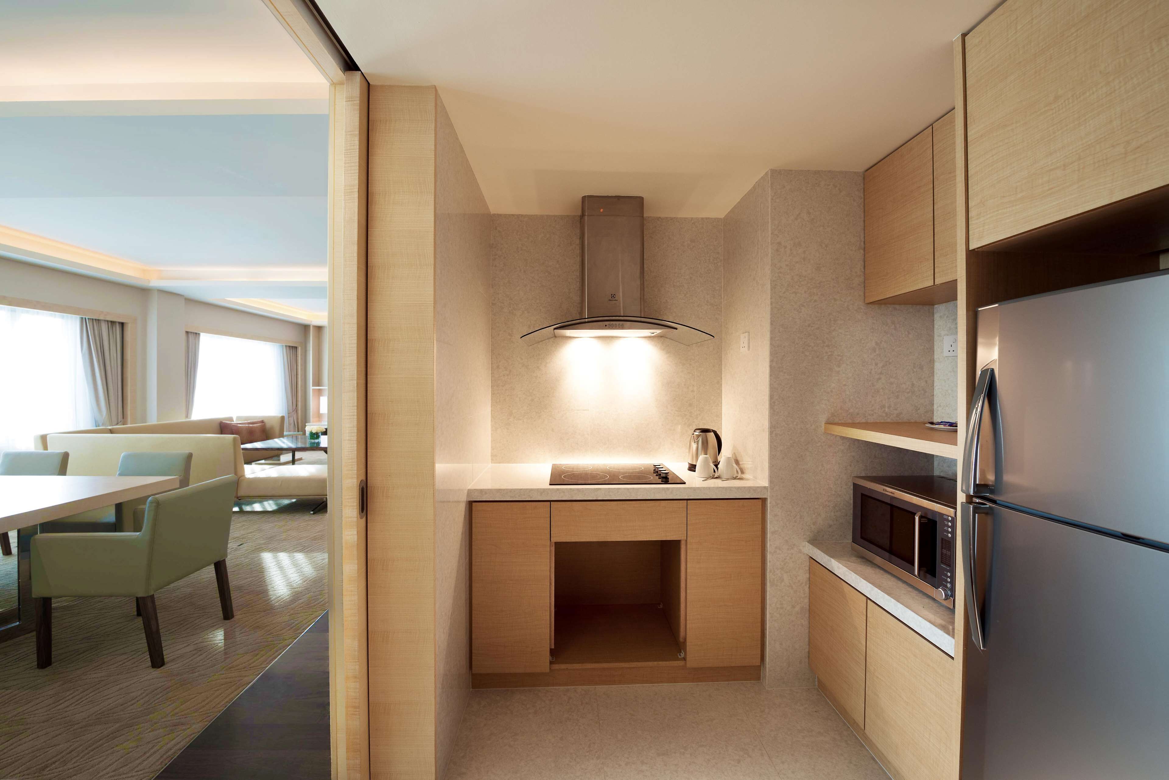 A compact kitchen with a microwave, a built-in oven, and a stainless steel refrigerator.