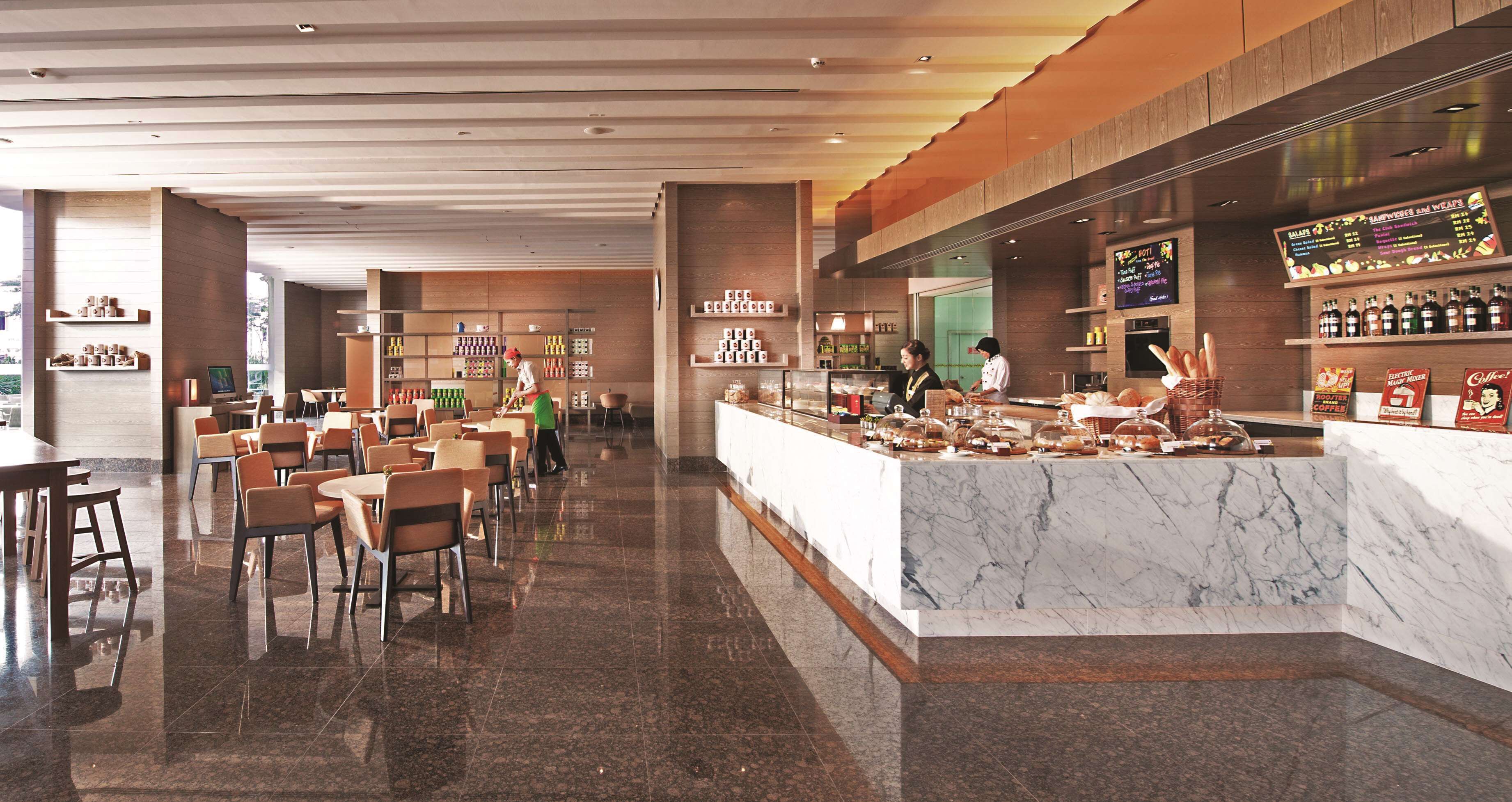 A modern hotel lobby with a marble reception desk, seating area, and a digital menu board.