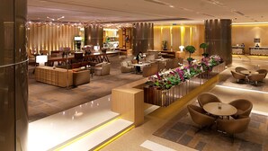 Un moderno vestíbulo de hotel con mostrador de recepción, zona de estar y una exhibición decorativa de plantas.