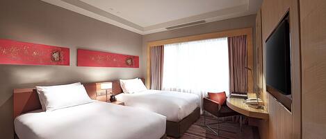 A hotel room with two beds, a desk with a chair, a television, and artwork on the wall.