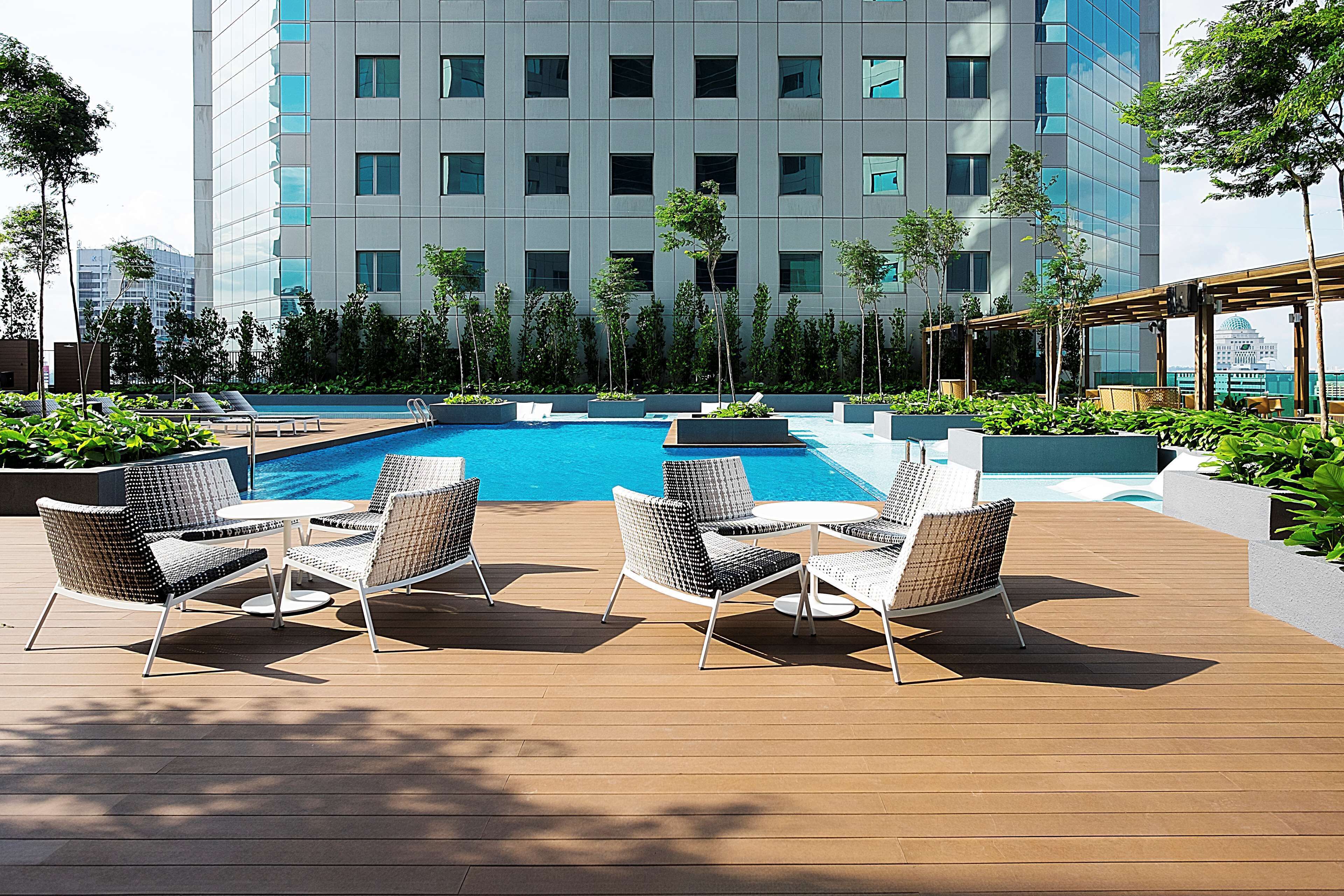 A rooftop pool area with lounge chairs and a view of a modern building.