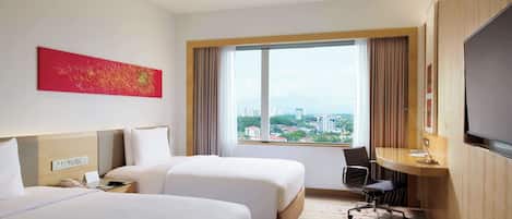 Habitación de hotel con dos camas, un escritorio, una silla, un televisor y un ventanal con vistas a la ciudad.