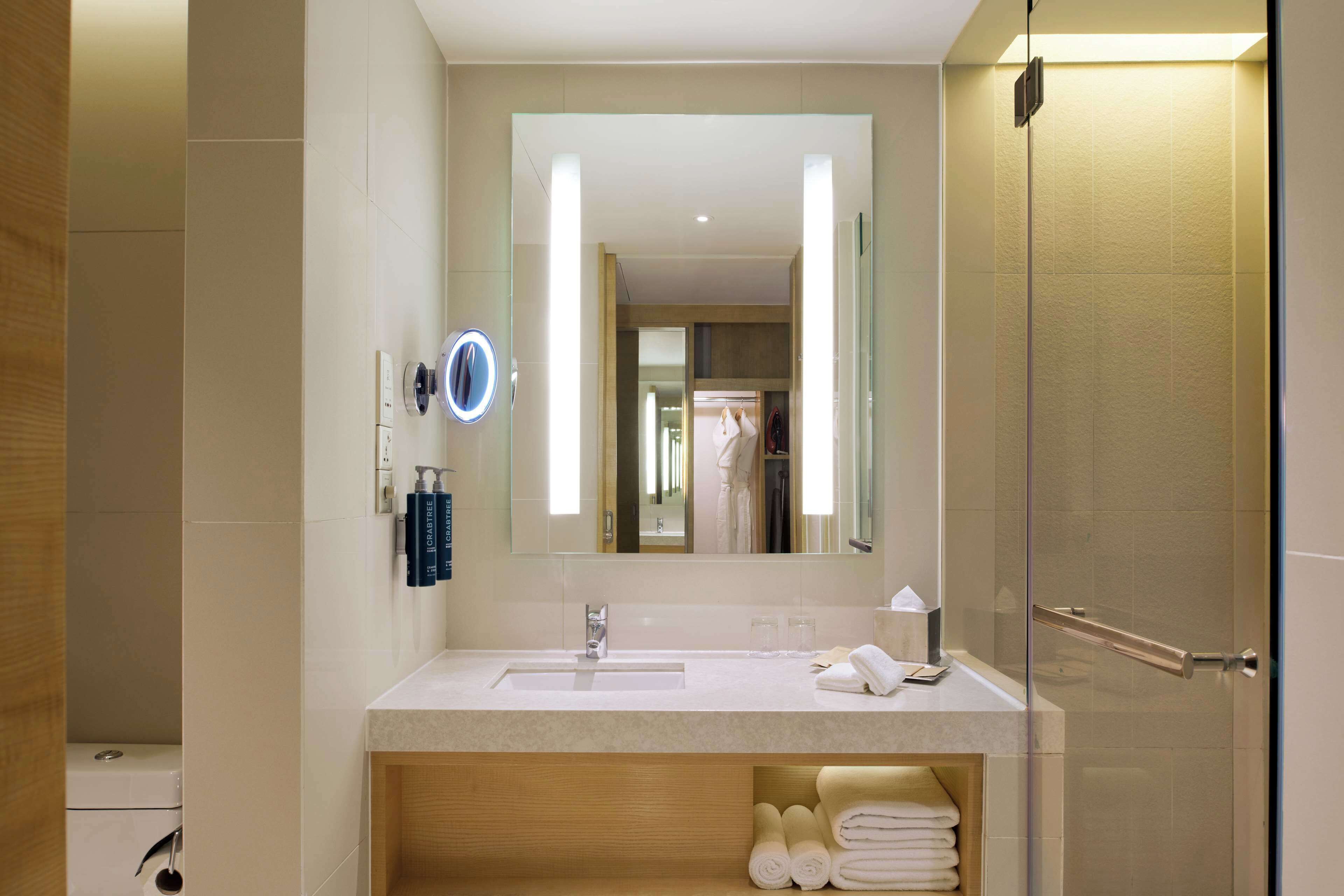 A modern bathroom with a large mirror, a sink, and a glass shower enclosure.