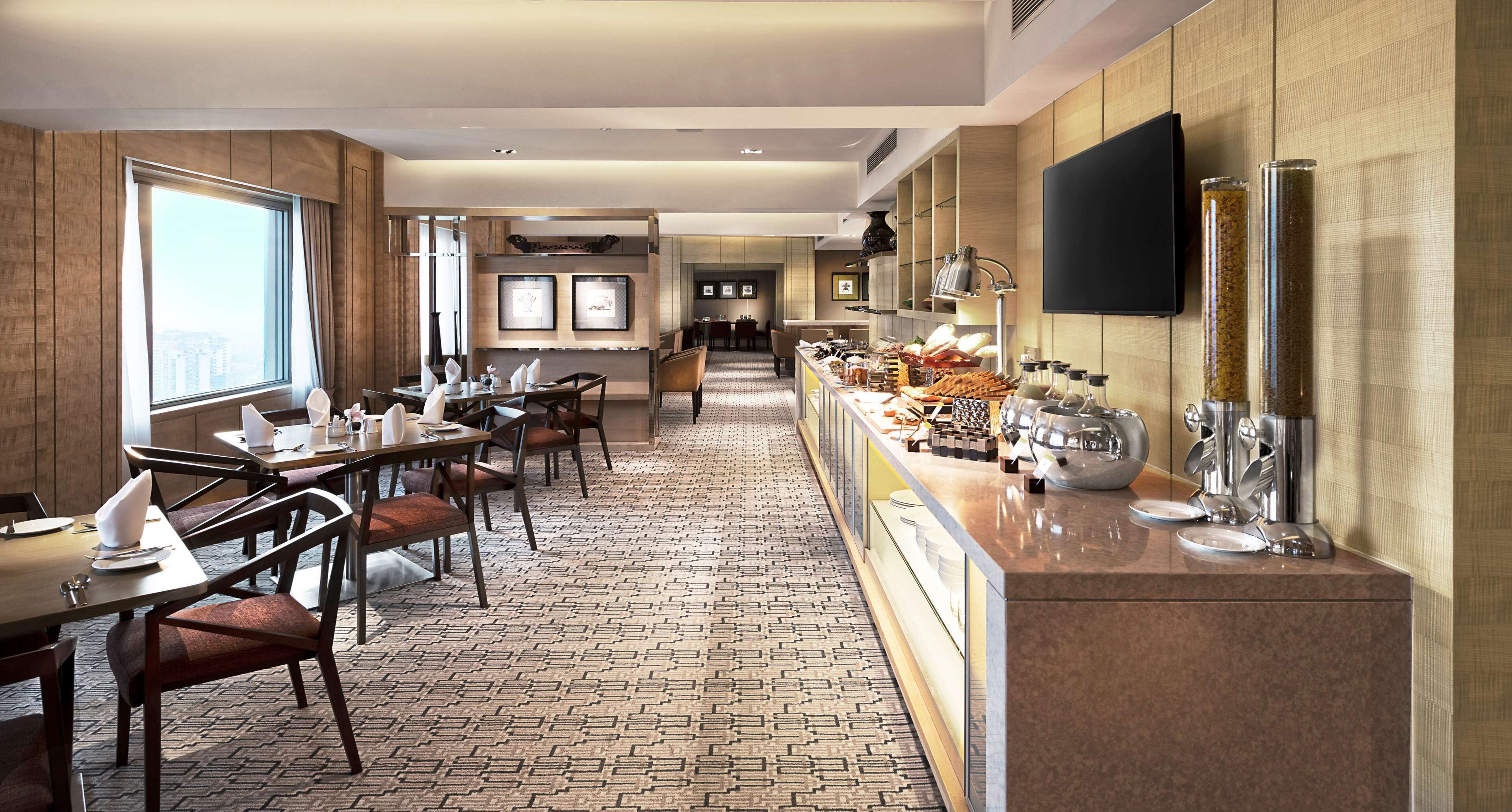 A hotel dining area with a long counter, multiple tables, and chairs.