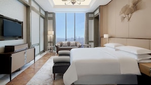 Une chambre d’hôtel moderne dotée d’un grand lit, d’une télévision, d’un canapé et offrant une vue sur la ville.