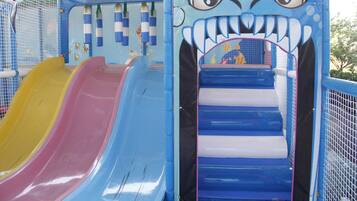 Zona de juegos infantiles con toboganes y una pared de escalar.