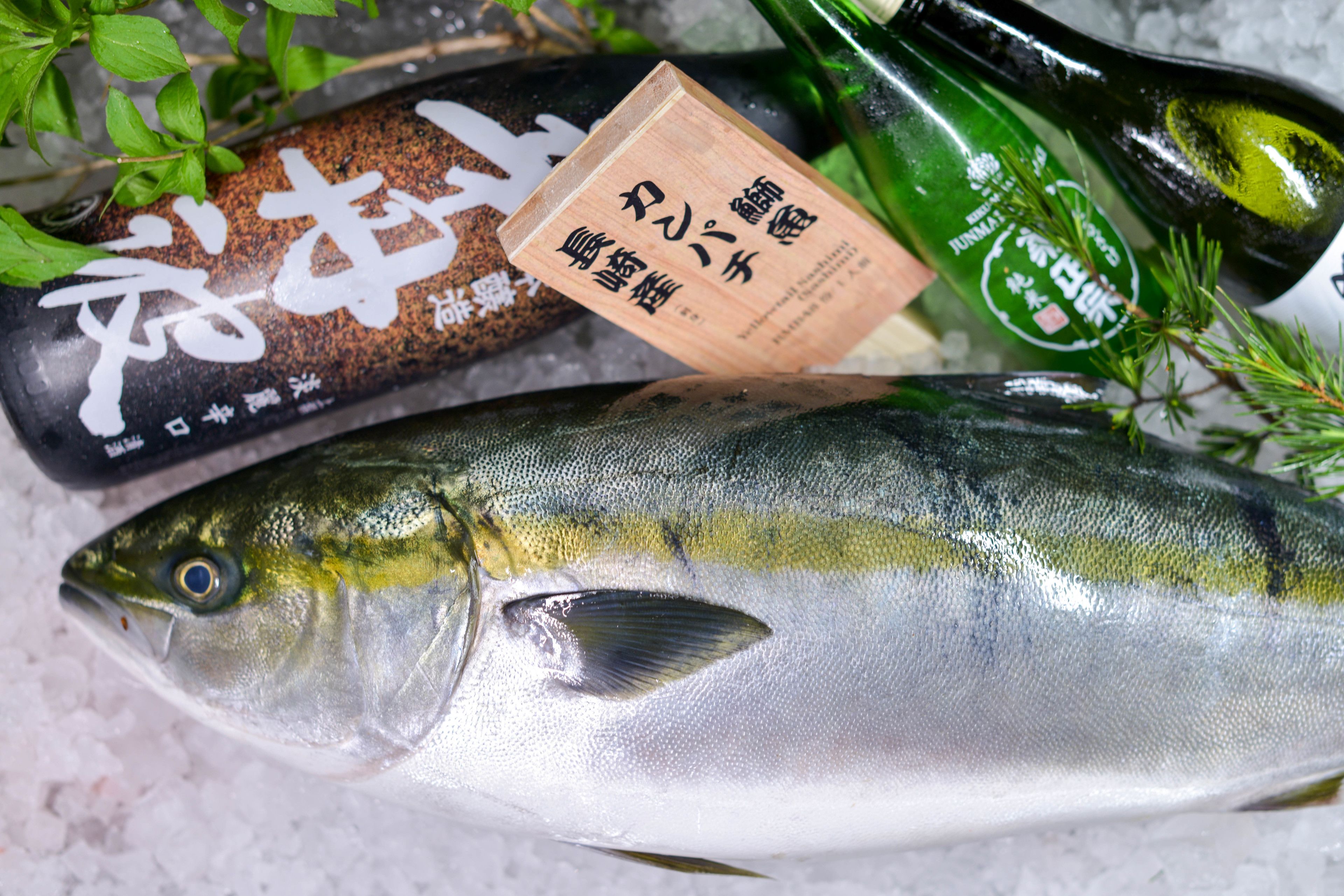 A fish on ice with a wooden label and a green bottle.