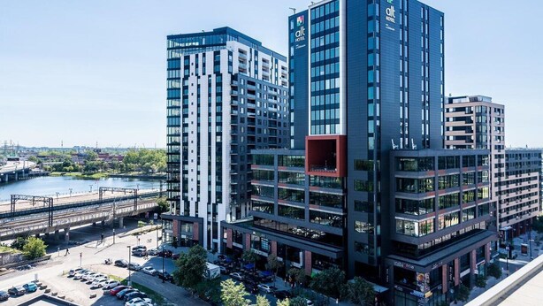 A modern hotel with multiple floors, large windows, and a prominent red section on the facade. - Hôtel Alt Montréal (Montreal)