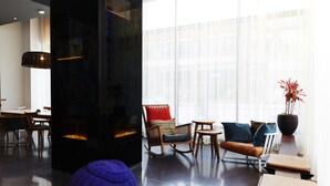 A modern living room with a fireplace, seating area, and large windows. - Hôtel Alt Montréal (Montreal)