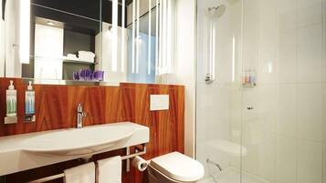 A modern bathroom with a wooden vanity, a toilet, and a glass shower enclosure.