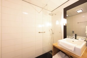 A modern bathroom with a glass-enclosed shower, a wooden vanity with a sink, and a large mirror. - Best Western Plus Hotel Restaurant Aduard (Aduard)