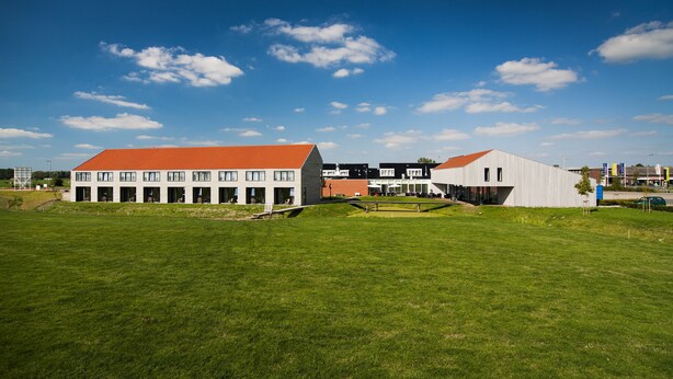 A modern building complex with multiple structures, including a large building with a red roof and a smaller white building. - Best Western Plus Hotel Restaurant Aduard (Aduard)