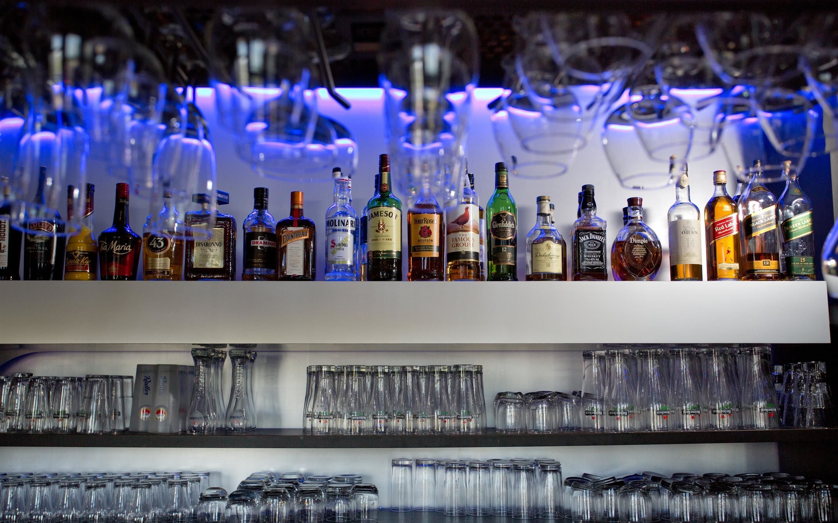 A bar with various liquor bottles and a large number of glasses.