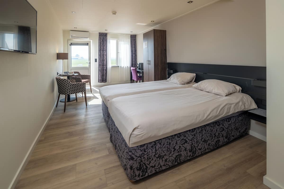 A modern hotel room with a large bed, a desk with a chair, and a TV mounted on the wall.