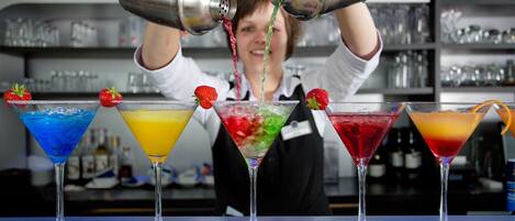 A bartender pouring a drink into a martini glass.