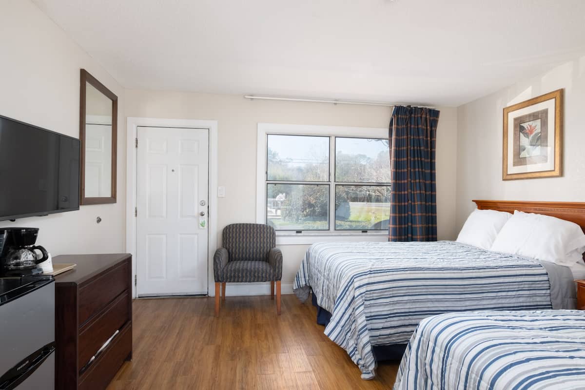 A hotel room with a bed, a chair, a television, and a window with curtains.