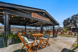 An outdoor seating area with wooden furniture and a sign reading "Suwannee River". - Suwannee Gables Motel and Marina (Old Town)
