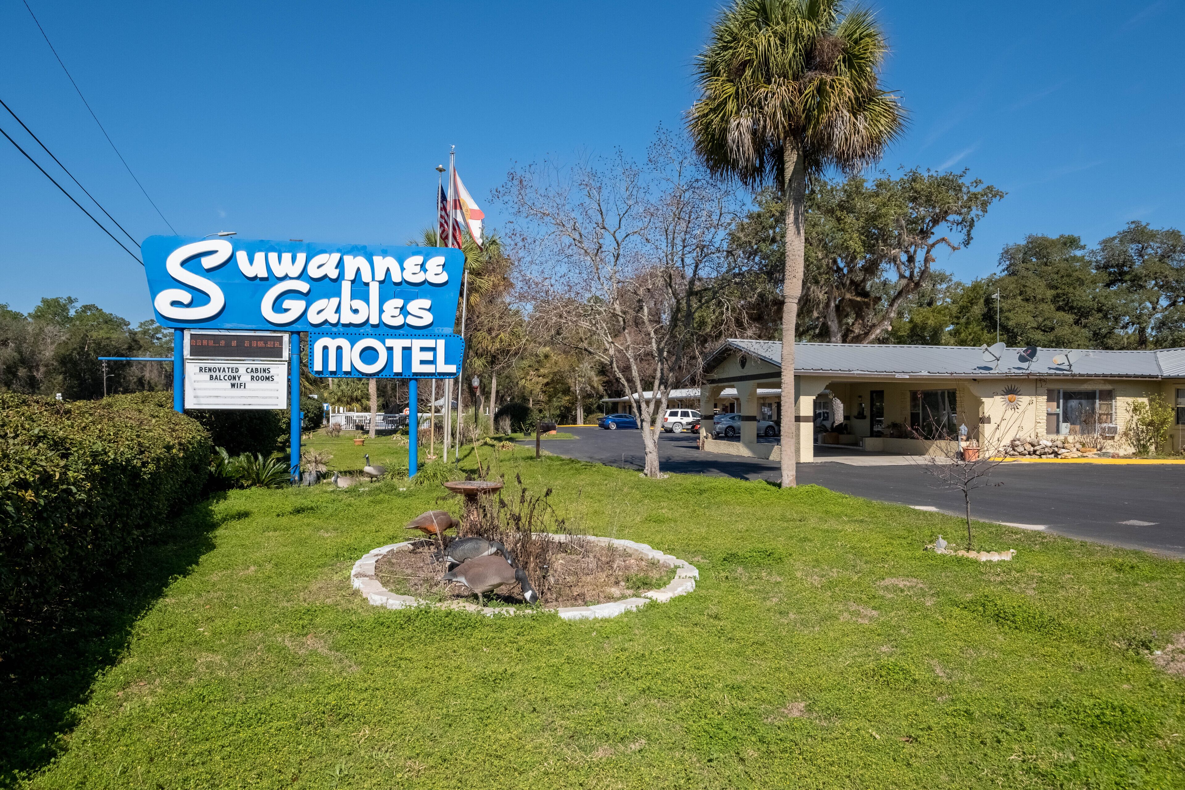 Ein Motel namens 'Suwannee Gables' mit einem Schild, renovierten Ferienhäusern und Balkonzimmern sowie WLAN.