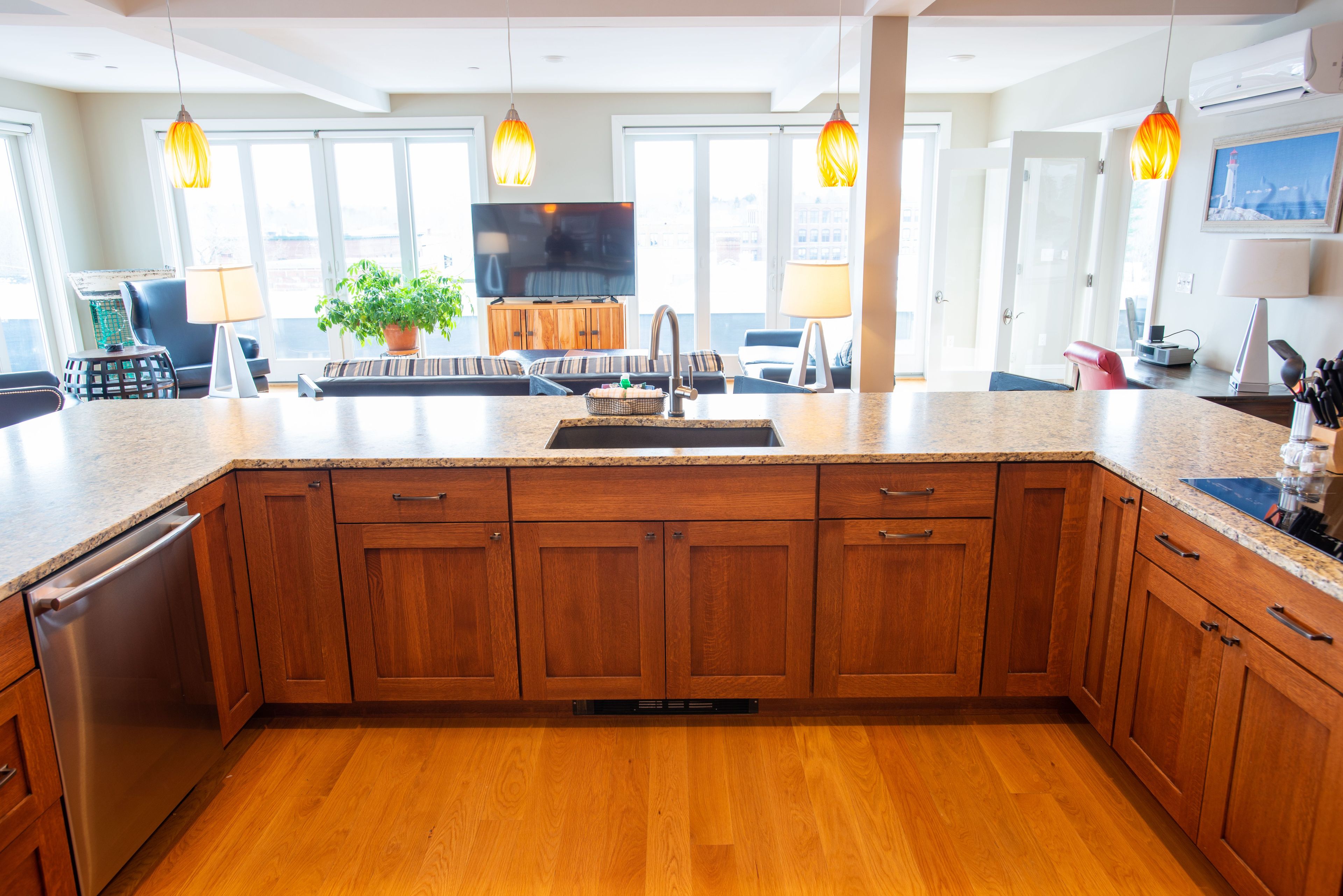 A modern kitchen with wooden cabinets, a granite countertop, and pendant lighting.
