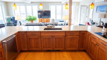 A modern kitchen with wooden cabinets, a granite countertop, and pendant lighting.