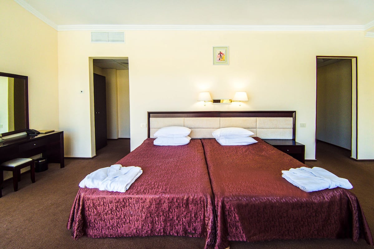 Ein Hotelzimmer mit zwei Betten, einem Schreibtisch und einem Spiegel.