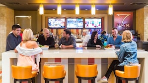 A bar area with multiple screens, bar stools, and a counter.