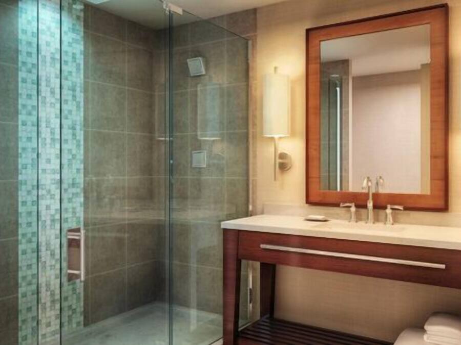 Un bagno moderno con cabina doccia in vetro, un mobile vanitario in legno e uno specchio grande.