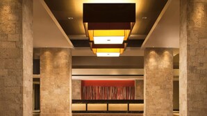 A spacious lobby with a patterned floor, a central red accent wall, and a modern ceiling light fixture.