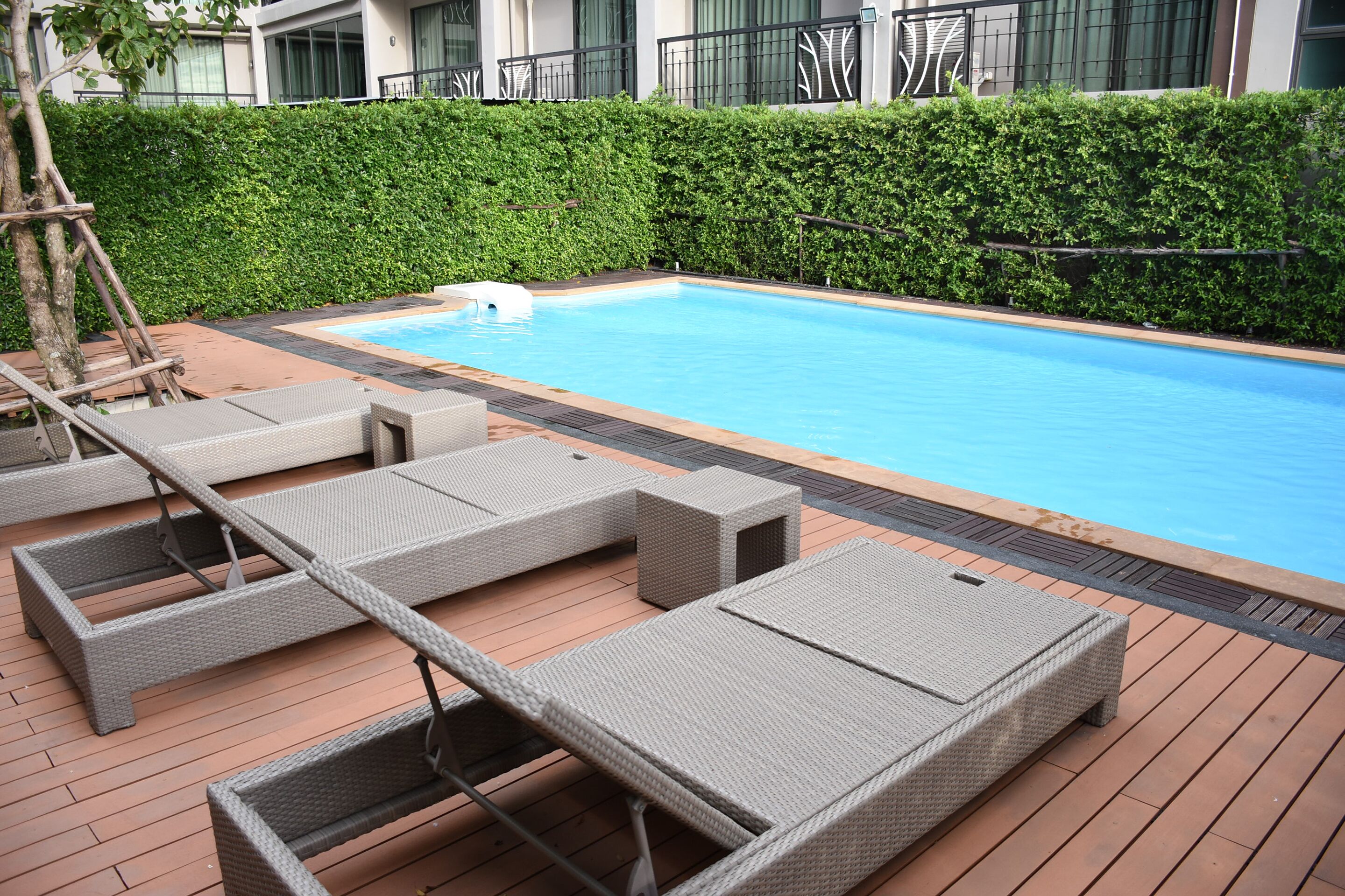 A swimming pool with lounge chairs and a wooden deck.