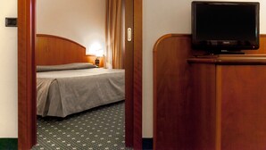 Habitación de hotel con cama, televisión sobre un aparador de madera y alfombra estampada.