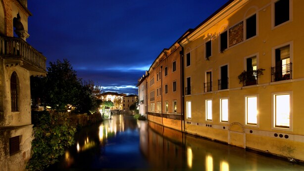 Un canal flanqueado por edificios, con balcones y ventanas que reflejan las luces.