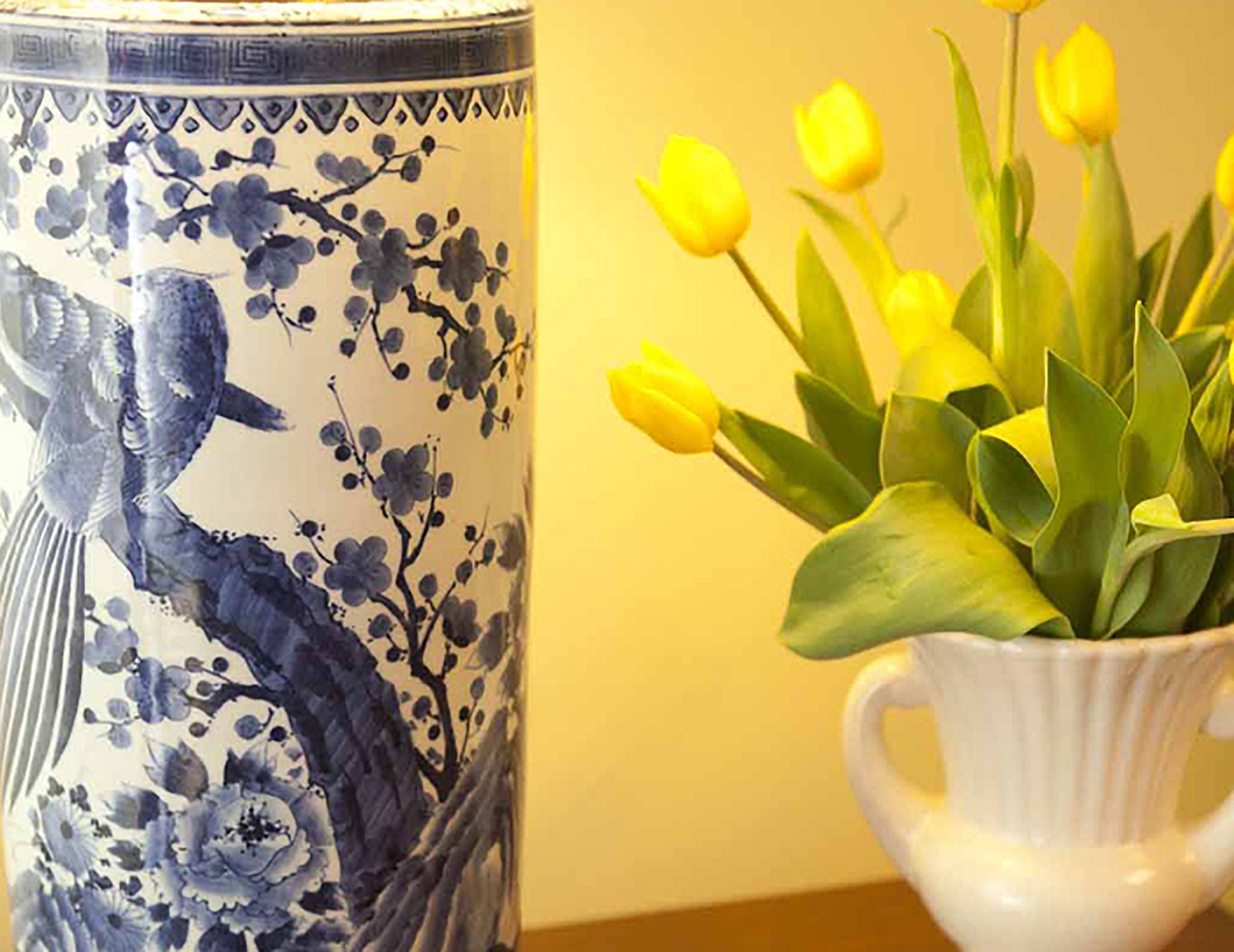 En keramisk vase med blomstermotiv og en hvid keramisk potte med gule tulipaner.