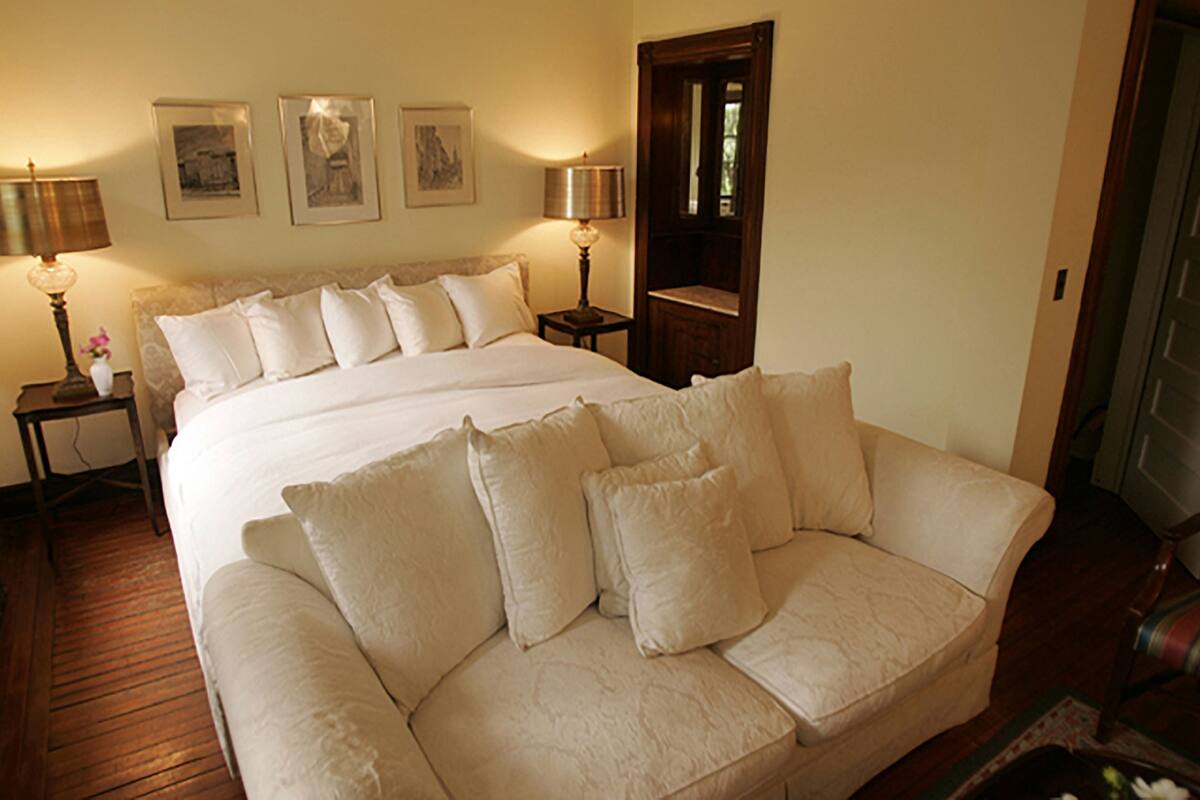 A bedroom with a large bed, two bedside tables with lamps, and three framed pictures on the wall.