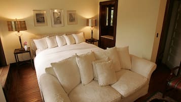 A bedroom with a large bed, two bedside tables with lamps, and three framed pictures on the wall.