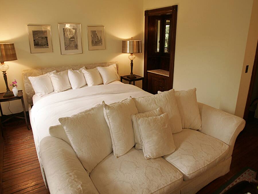 A bedroom with a large bed, two bedside tables with lamps, and three framed pictures on the wall.