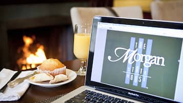 Una computadora portátil sobre una mesa con un muffin y un vaso de jugo de naranja. La pantalla de la computadora muestra "The Morgan State House".