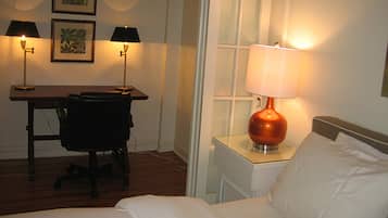 A hotel room with a bed, a desk, two lamps, and a chair.