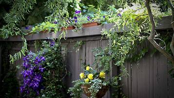 Une clôture en bois ornée de plantes grimpantes et de suspensions de jardinières.