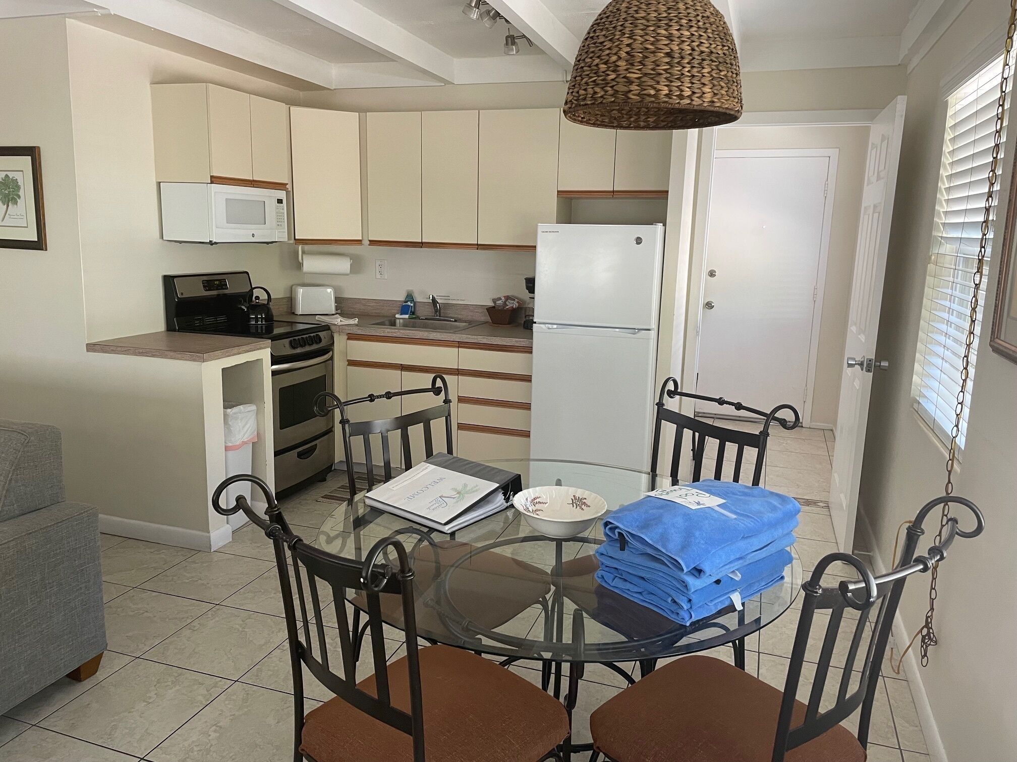 A compact kitchen with a dining table, chairs, and a refrigerator.