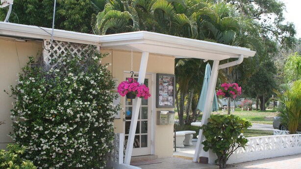 A building with a covered entrance, a small porch, and a door with a sign. - Venice Beach Villas (Venice)