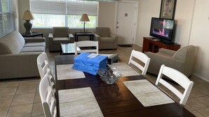 A living room with a dining table, chairs, sofas, a TV, and a ceiling fan. - Venice Beach Villas (Venice)