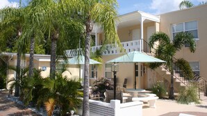 A courtyard with palm trees, outdoor seating, and a building with a balcony. - Venice Beach Villas (Venice)