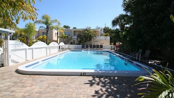 Relax by the pool surrounded by lush greenery and lounge chairs.