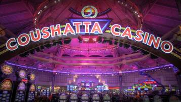A casino interior with a prominent sign reading "COUSHATTA CASINO" and multiple slot machines.