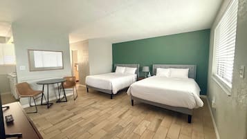Quarto de hotel com duas camas, uma escrivaninha e uma cadeira.