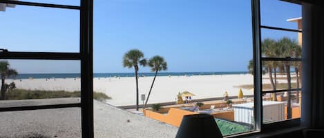 A beach view from a window with a lamp on the windowsill.
