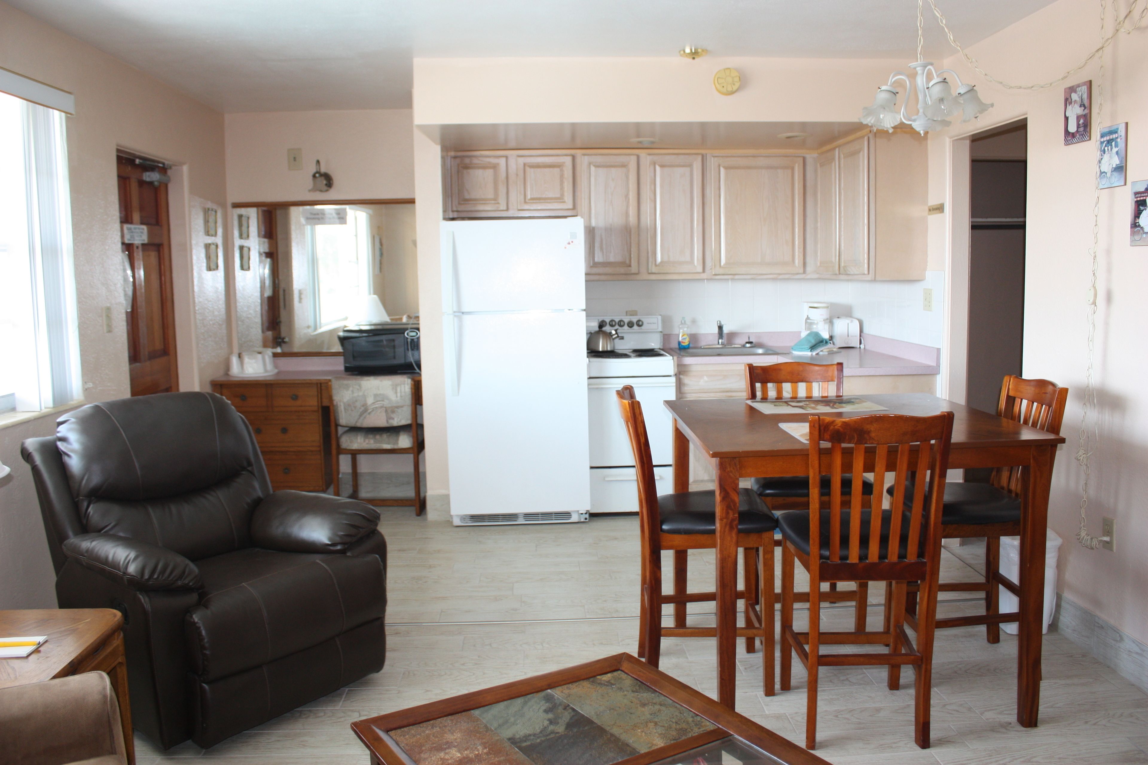 A compact living space with a dining area, kitchen, and a leather recliner.