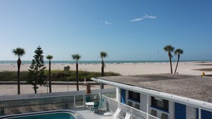 A beach view from a building with a pool, palm trees, and a beach in the background. - iBeach Resort (Treasure Island)